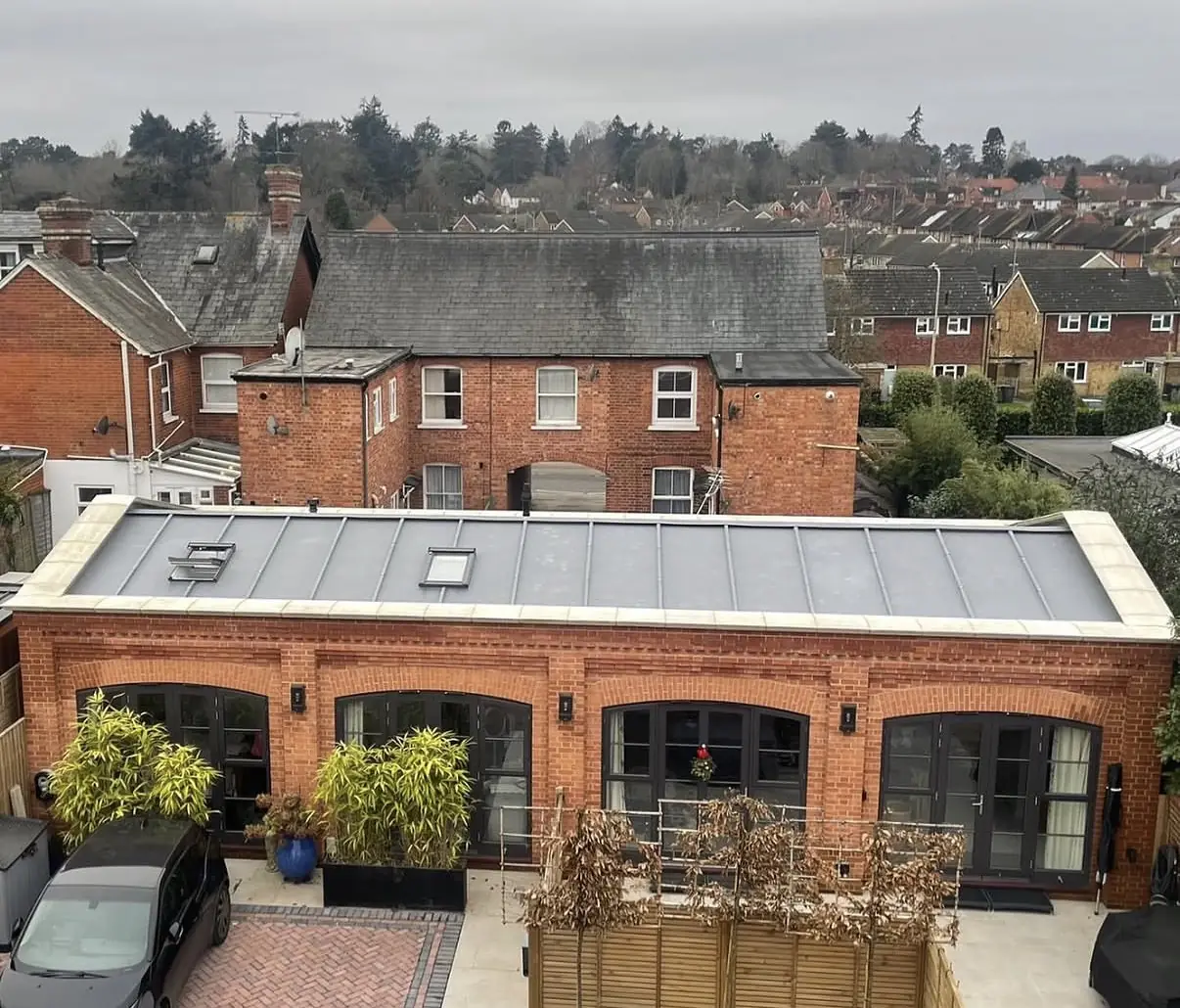 Standing seam zinc roof with two rooflights on a single-storey red-brick building with pale coping