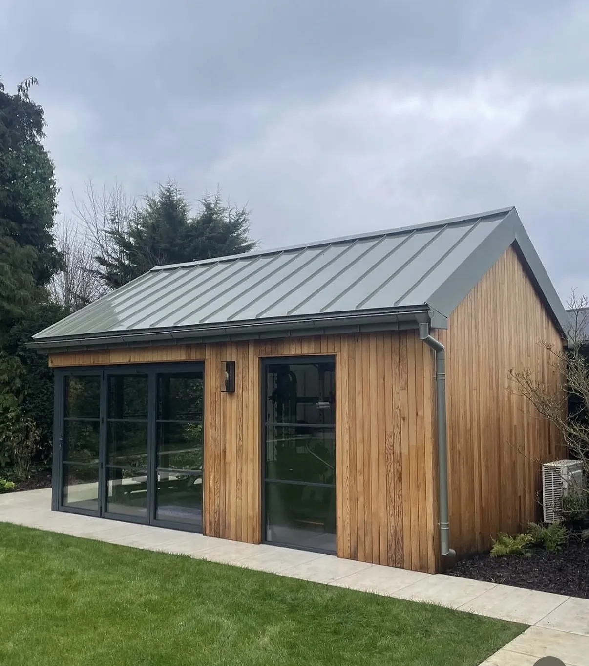 Standing seam zinc roof on a garden room with natural cedar cladding